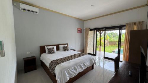a bedroom with a bed and a large window at Shima Tunjung in Darmasaba