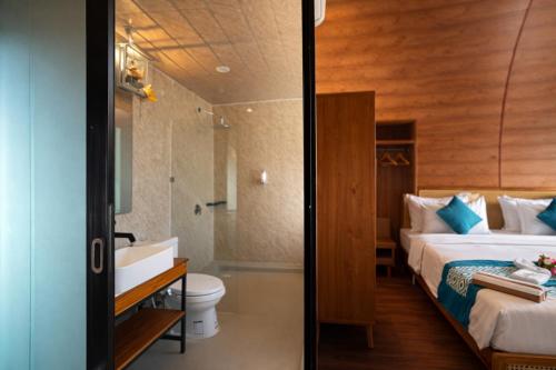 a bedroom with a bed and a bathroom with a sink at Nirvana Hotel Resort Tetebatu in Tetebatu