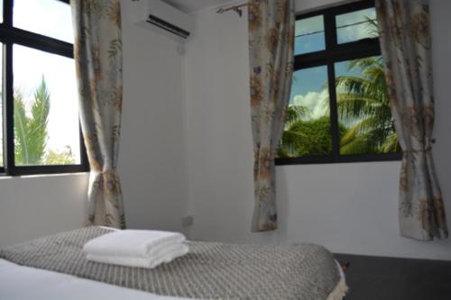 a bedroom with a bed with two windows and towels at Airways Residence in Plaine Magnien