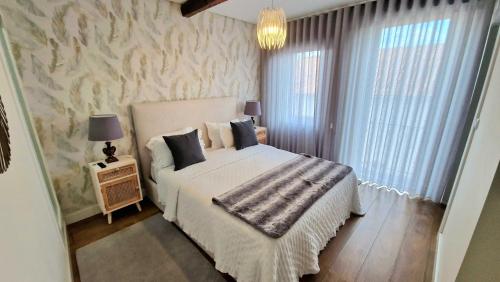 a bedroom with a white bed and a window at Casa do Tablado - Foz Côa in Vila Nova de Foz Coa