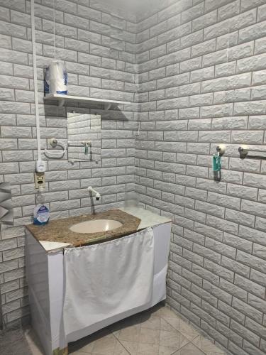 a bathroom with a sink and a white brick wall at Casarão 3 quartos com ar e garagem in Belém