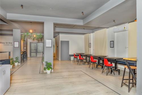 a dining room with tables and red chairs at Loop by Zolo Baani Square, Gurugram in Gurgaon