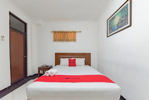 a bedroom with a large bed with a red blanket at RedDoorz Plus at Buah Batu in Bandung
