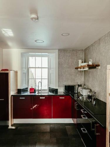 a kitchen with red cabinets and a red counter top at The Seadoor, Shetland Islands in Lerwick