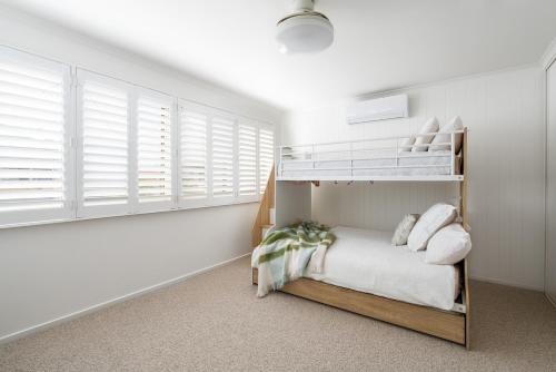 a bedroom with a bunk bed and white walls at Fireplace & Winter Swells, 800m to the beach in Ocean Grove