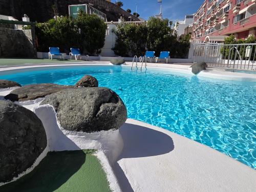 a large swimming pool with rocks and blue chairs at Estrella y mar in La Estrella
