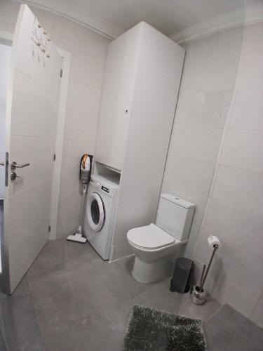 a bathroom with a toilet and a washing machine at RJ Summer in Sagres