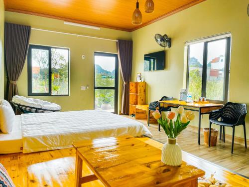 a bedroom with a bed and a table and windows at The Sam Home in Nguyên Ngoại