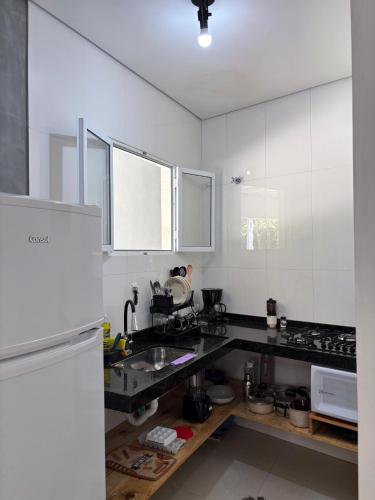 a kitchen with white cabinets and a black counter top at Chalé Encanto Paraty in Paraty