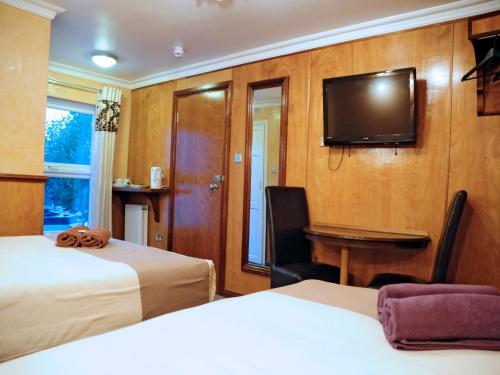 a hotel room with two beds and a flat screen tv at Cricklewood Lodge Hotel in London