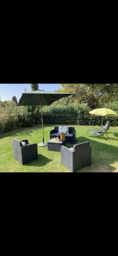 two couches and an umbrella in the grass at Loue rez de maison 3mn de la plage in Canly