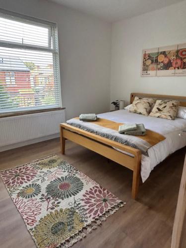 a bedroom with a bed with a rug and a window at Stylish Didsbury House in Manchester
