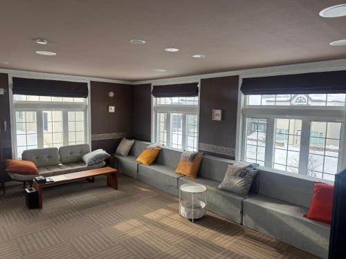 a living room with a long couch with colorful pillows at BIEI TERRACE 2nd Floor - 2F専用独立玄関 - 2F占有127平米2LDK - 大型バスルーム, 85型スマートTV, 無料Wi-Fi -駅前通り景観条例指定地区 in Biei