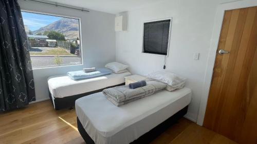 two beds in a room with a large window at Qt inntouch in Queenstown