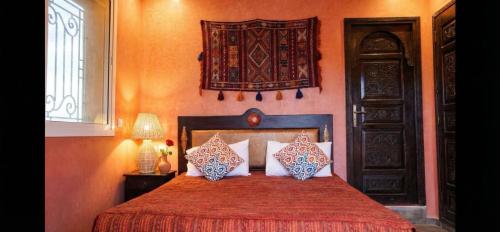 a bedroom with a red bed with two pillows at Résidence Palmariva Aglou in Tiznit