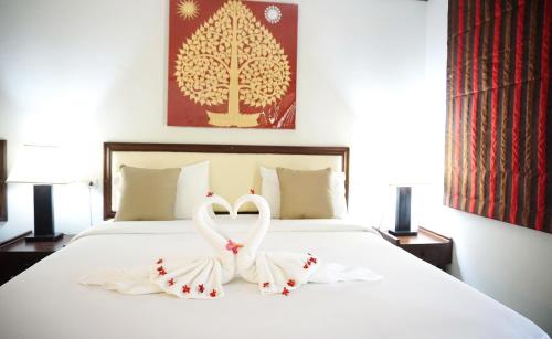 two swans dressed in white are sitting on a bed at Lamai Inn 99 Bungalows in Lamai