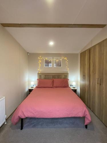 a bedroom with a large bed with a pink bedspread at 230 Unity Holiday Resort 6 Birth cosy and secure property next to all shops and entertainment passes optional in Brean