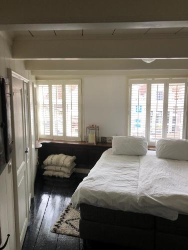 a bedroom with a large bed and two windows at De Kleine Prins Enkhuizen in Enkhuizen