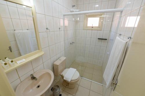 a white bathroom with a toilet and a sink at Pousada Prime Gramado in Gramado