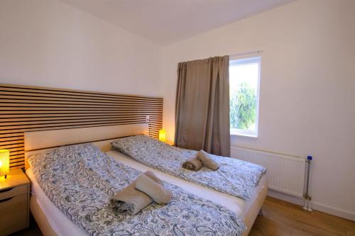 a bedroom with two beds with pillows and a window at Golden house - Bungalow near the beach in Noordwijkerhout