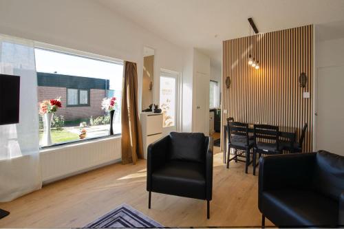 a living room with a table and chairs and a window at Golden house - Bungalow near the beach in Noordwijkerhout