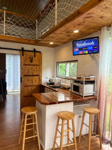 a kitchen with two bar stools and a microwave at Tiny House in Dahilayan in Manolo Fortich