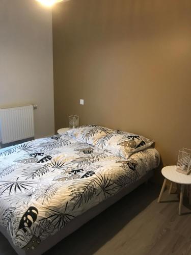 a bed with a black and white comforter in a room at Appartement récent et à la déco moderne in Damgan