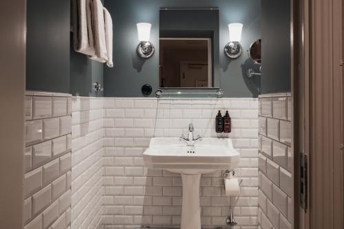 a white bathroom with a sink and a mirror at Home Hotel Baltzar in Malmö