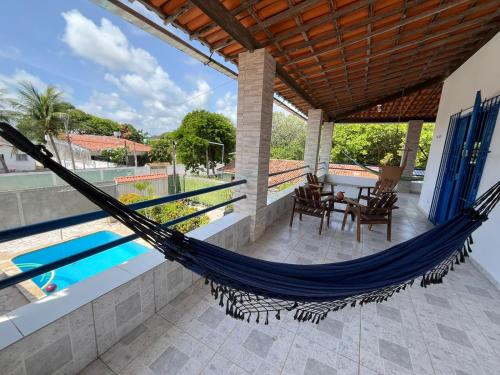 a hammock on a patio next to a swimming pool at Canto da Ita - Próxima a praia com piscina e churrasqueira in Itamaracá