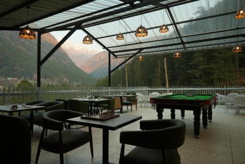 a restaurant with tables and chairs with mountains in the background at The Udit By West Western - Central Heated and Air Cooled - River View & Roof Top cafe & Bar in Kasol