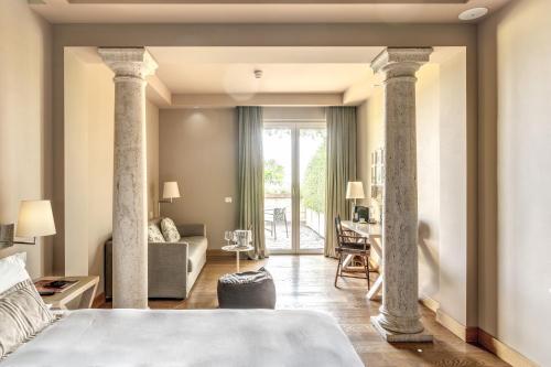 a bedroom with columns and a living room with a couch at Tenuta De L'Annunziata - Natural Relais in Uggiate