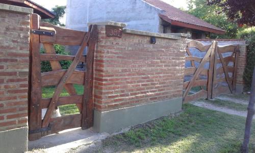 una valla de ladrillo con una puerta de madera en un patio en La Casita de Sil en Mina Clavero