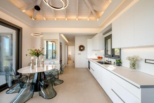una cucina con mobili bianchi, tavolo e sedie di Avaton a Vátos