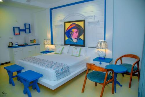 a bedroom with a large white bed and blue chairs at Norea Sands in Bentota