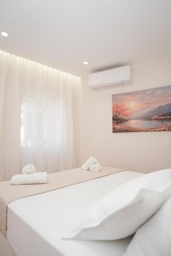 two beds in a white room with a picture on the wall at Pearl Port House in Ágios Rókkos