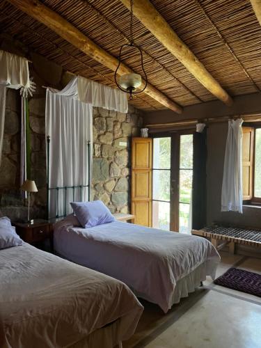 a bedroom with two beds and a stone wall at Quinta La Paceña in Tilcara