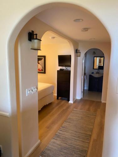 a room with a bedroom with a bed and a television at Carmel Dolores Cottages in Carmel