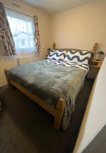 a bedroom with a wooden bed with a zebraandan at 66 The Firs - Southview Holiday Park in Skegness