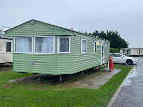 a green tiny house is parked in a yard at 66 The Firs - Southview Holiday Park in Skegness