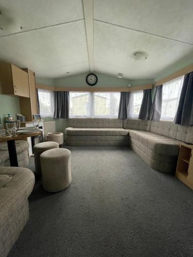 a living room with couches and a clock on the wall at 66 The Firs - Southview Holiday Park in Skegness