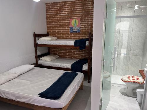 a room with three bunk beds and a shower at hostel Bike Point Caraguatatuba in Caraguatatuba