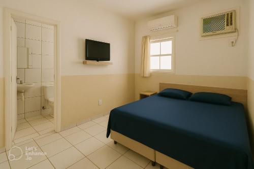 a bedroom with a bed and a bathroom with a television at Alojamento Pousada Economica Canoas in Canoas