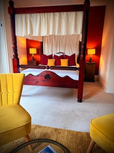 a bedroom with a canopy bed with red and yellow pillows at Swan Hotel Forton in Forton