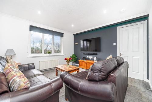 a living room with two leather couches and a tv at Prime Commuter Executive Apartment Dunfermline in Dunfermline