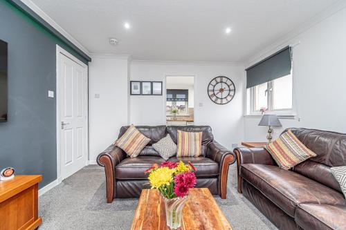 a living room with two leather couches and a table at Prime Commuter Executive Apartment Dunfermline in Dunfermline