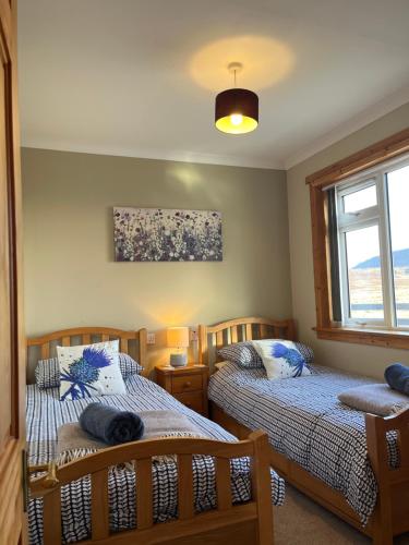 a bedroom with two beds and a window at The Homer in Kilmuir