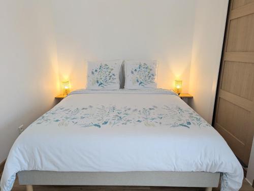a bedroom with a large white bed with blue flowers at Gîte La Clef du Sud - Cosy 4 pers, parking gratuit, EuroVelo 8 in Salernes
