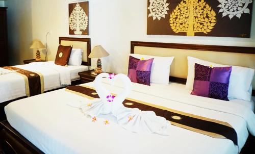 two beds in a hotel room with white and purple pillows at Lamai Inn 99 Bungalows in Lamai