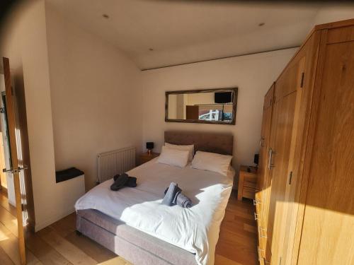 a bedroom with a bed with white sheets and a mirror at THE BOATHOUSE. The gateway to the Jurassic Coast in Hamworthy