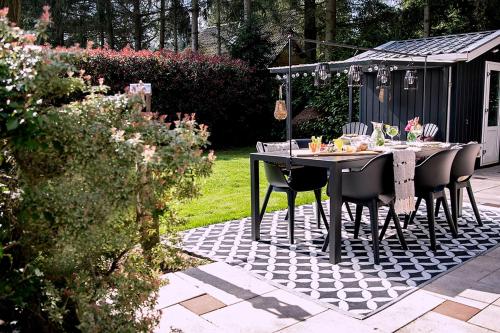 a table and chairs on a patio in a garden at Natuurhuisje met omheinde tuin hond welkom stijlvol ingericht StayatSas Julia in Epe